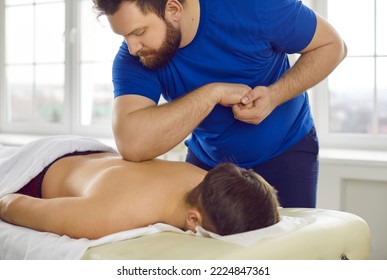 Male masseur give massage to client in medical clinic. Man physiotherapist relieve back pain work with customer in cabinet in wellness center. Physiotherapy and rehabilitation concept.