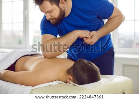 Male masseur give massage to client in medical clinic. Man physiotherapist relieve back pain work with customer in cabinet in wellness center. Physiotherapy and rehabilitation concept.