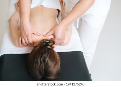 Male Masseur With Strong Hands Professionally Massaging Scapulas And Shoulders To Female Client. Beautiful Naked Young Woman With Perfect Skin Getting Relaxing Back Massage At Spa Salon.