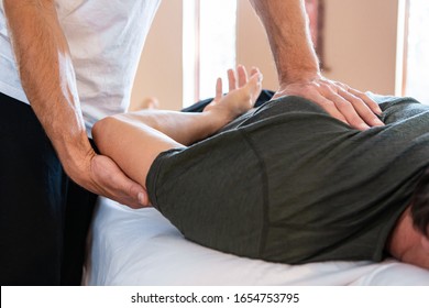 Männliche Masseur-Therapeuten Hände, die auf starke männliche therapeutische Körpermassage. Professionelle Masseurin, die einem Sportler die Massage zurückgibt