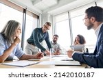 Male mature caucasian ceo businessman leader with diverse coworkers team, executive managers group at meeting. Multicultural professional businesspeople working together on research plan in boardroom.