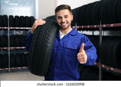 Male Mechanic With Car Tire In Auto Store