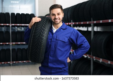 Male Mechanic With Car Tire In Auto Store