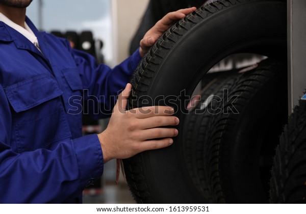 Male\
mechanic with car tire in auto store,\
closeup