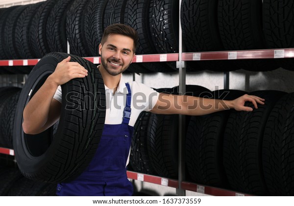 Male mechanic with
car tire in auto store