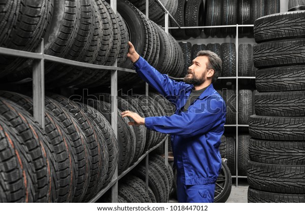 Male mechanic\
with car tires in automobile\
store