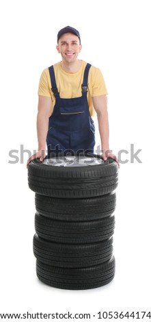 Male mechanic with car tires on white background