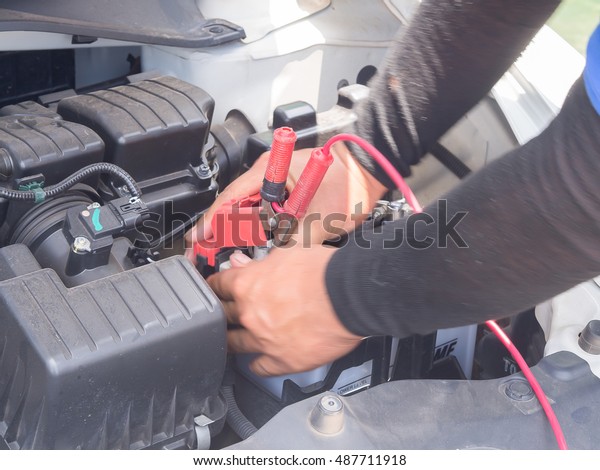 Male mechanic changing\
car battery\

