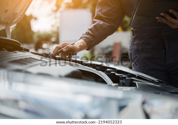 Male mechanic is checking the car\
maintenance lists for maintenance and fixing the\
car.