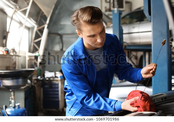 Male mechanic checking engine oil level in car\
service center