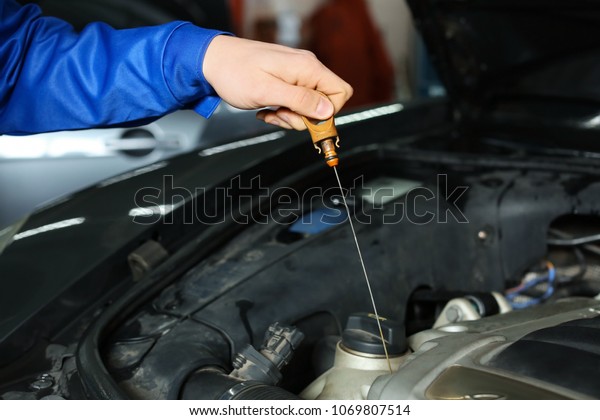 Male mechanic checking engine oil level in car\
service center