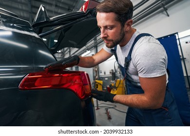 Male mechanic checking the level of car taillight