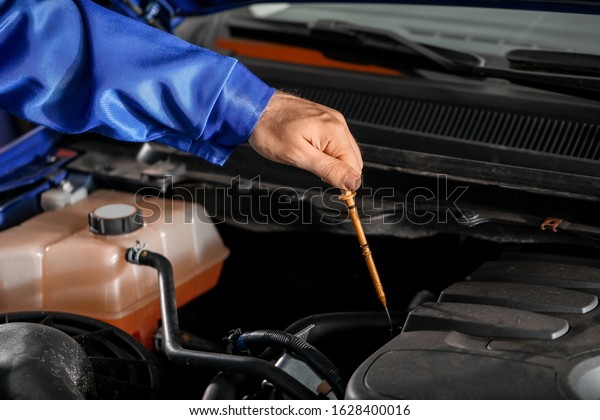 Male\
mechanic checking level of oil in car\
engine