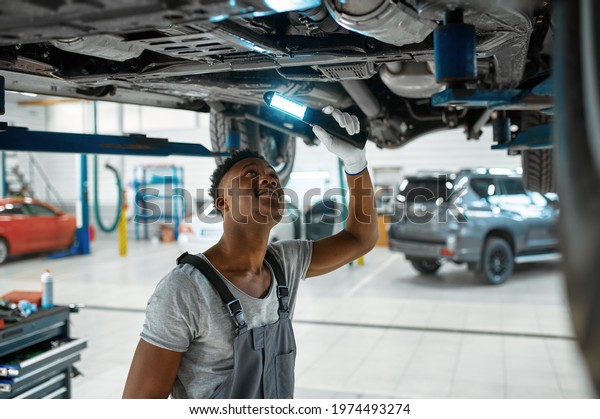 Male\
mechanic checks car suspension, auto\
service