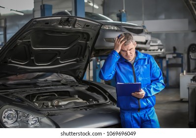Male mechanic with clipboard near car in service center - Shutterstock ID 1069696049