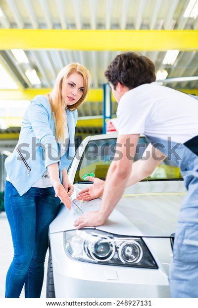Male mechanic examine car finish on dents or scratches
in workshop 
