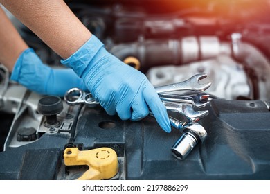 Male Mechanic Help Woman Solve The Problem Of Car Breakdown. He Lifts The Hood Of The Car To Repair The Damaged Part. Man's Hands Close Up