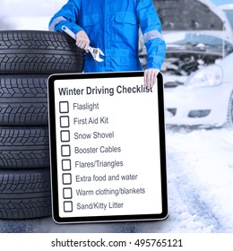 Male Mechanic Leaning On A Stack Of Tires While Holding A Winter Driving Tips And A Wrench, Shot Outdoors