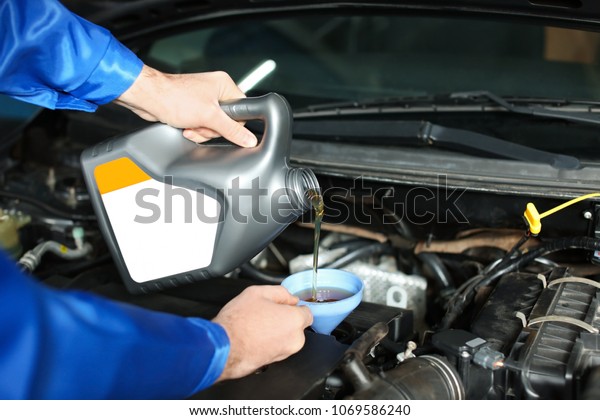 Male\
mechanic refilling car oil in service\
center