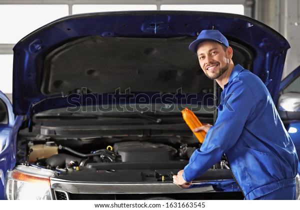 Male\
mechanic refilling car oil in service\
center