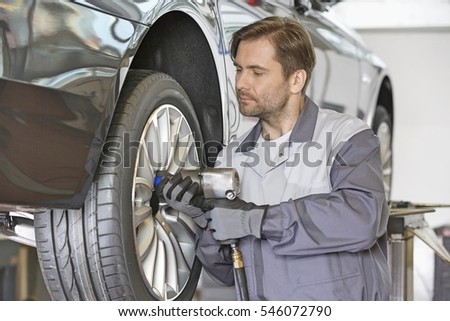 Male mechanic repairing car's wheel in workshop