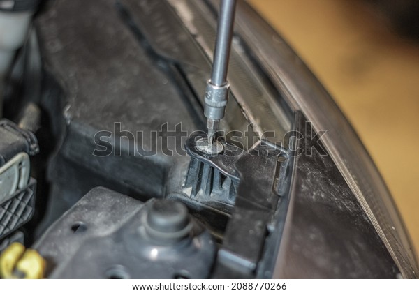 A male
mechanic repairs a car in the garage. The concept of a garage for
car maintenance and car service. Hands in close-up and a wrench.
The mechanic unscrews the car's
light.