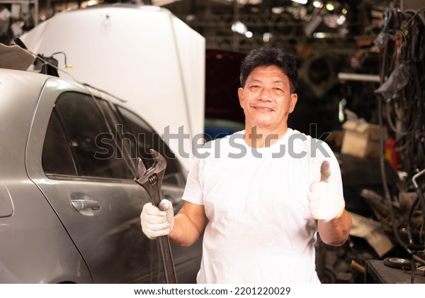 male mechanic repairs car in\
garage. Car maintenance and auto service garage concept. Auto\
mechanic working in garage.Car Mechanic Detailed Vehicle\
Inspection.