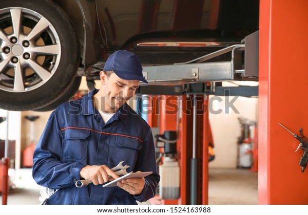Male\
mechanic with tablet computer in car service\
center