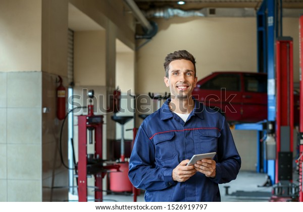 Male\
mechanic with tablet computer in car service\
center