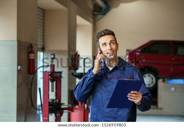 Male\
mechanic talking by phone in car service\
center