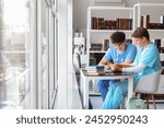 Male medical interns studying at table in library