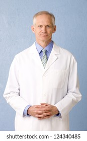 Male Medical Professional In Lab Coat On Blue Background Three Quarter Length