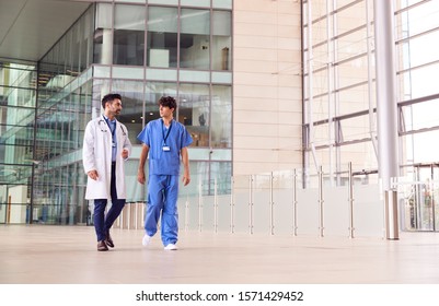 Male Medical Staff Talking As They Walk Through Lobby Of Modern Hospital Building - Shutterstock ID 1571429452