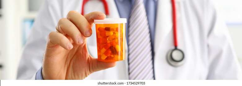Male medicine doctor hand holding and offering to patient jar of pills. Medical care prescription pharmacology insurance concept. Giving or showing medications to patient. Physician ready to help - Shutterstock ID 1734529703