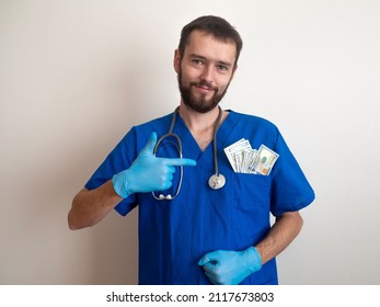 Male Medicine Doctor Holding Money Dollars Banknotes In Pocket. Payment Salary For The Doctor And Nurses Work. Payment To Employees In The Red Zone. Award To Doctors Working With Covid Patients