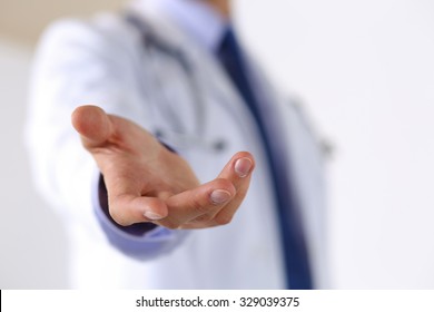 Male medicine doctor offering helping hand in office closeup. Friendly and cheerful gesture. Medical cure and tests advertisement concept. Physician ready to examine and save patient