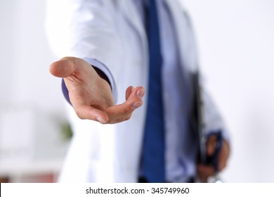 Male medicine doctor offering helping hand in office closeup. Friendly and cheerful gesture. Medical cure and tests advertisement concept. Physician ready to examine and save patient - Shutterstock ID 345749960
