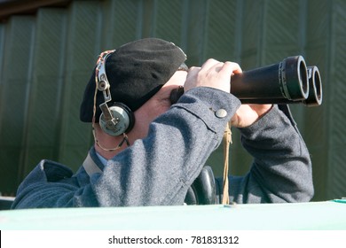 Male military personnel peering through a pair of huge binoculars outdoors - Powered by Shutterstock