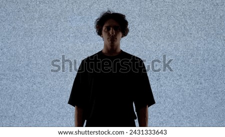 Male model against digital wall. Man silhouette posing on runaway catwalk fashion show in front of digital screen wall glitch background in club.