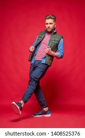 Male Model Posing In Casual Clothes. Fashion Portrait, Studio Shot, Red Background