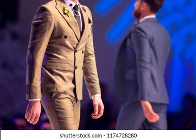 Male Model Walks The Runway In Beige Suit During A Fashion Show. Fashion Catwalk Event Showing New Collection Of Clothes.