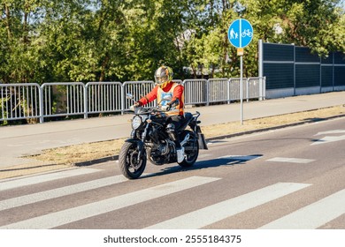 Male motorcyclist on black motorcycle participating in training on city road. Wearing protective helmet and bright safety vest, navigates crosswalk during motorcycle driving school session. - Powered by Shutterstock