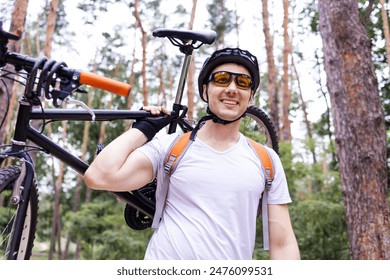 Male mountain biker carrying bicycle in the forest on a sunny day. - Powered by Shutterstock