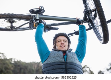 Männlicher Mountainbiker mit Fahrrad im Wald an einem sonnigen Tag