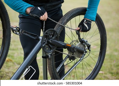 Male Mountain Biker Fixing His Bike Chain In The Forest