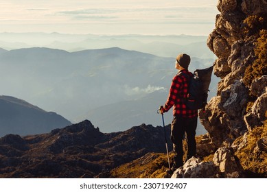 male mountaineer with red checkered shirt and backpack contemplating the sunset on a mountain. hiker on a mountain route. sport and adventure. - Powered by Shutterstock