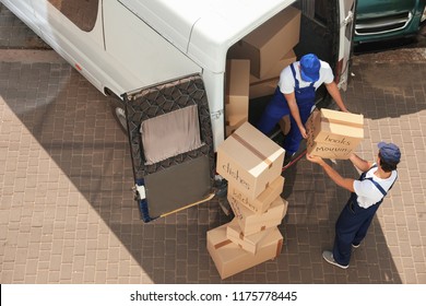 Male movers unloading boxes from van outdoors, above view
