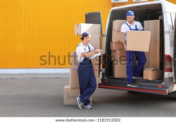 Male movers\
unloading boxes from van\
outdoors