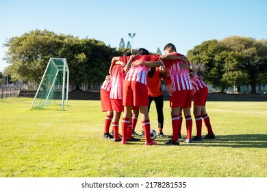 Male multiracial players in red uniform with arms around discussing and huddling at playground. Summer, match, motivation, meeting, unaltered, soccer, sport, teamwork, togetherness and competition. - Shutterstock ID 2178281535