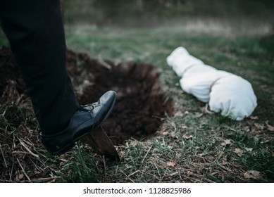 Male Murderer With A Shovel  Is Digging A Grave